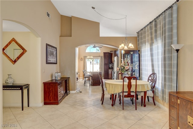 tiled dining area featuring an inviting chandelier and high vaulted ceiling