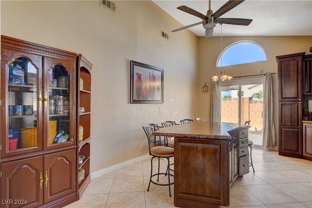 kitchen featuring ceiling fan with notable chandelier, a kitchen island, vaulted ceiling, and a breakfast bar