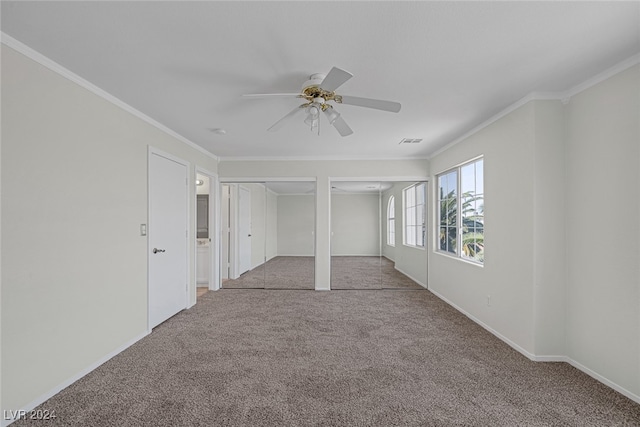 unfurnished bedroom with ornamental molding, two closets, light colored carpet, and ceiling fan