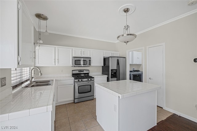 kitchen with white cabinets, hanging light fixtures, stainless steel appliances, sink, and a center island