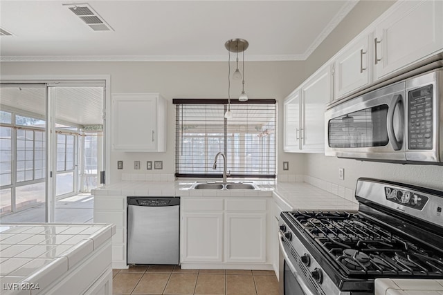 kitchen with white cabinets, tile countertops, ornamental molding, sink, and stainless steel appliances