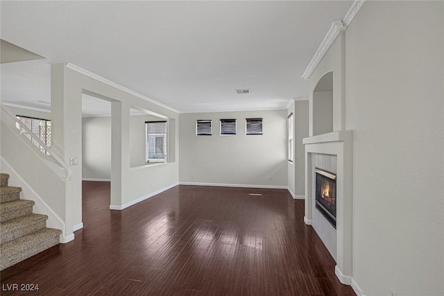 unfurnished living room featuring a healthy amount of sunlight, ornamental molding, a fireplace, and dark hardwood / wood-style floors