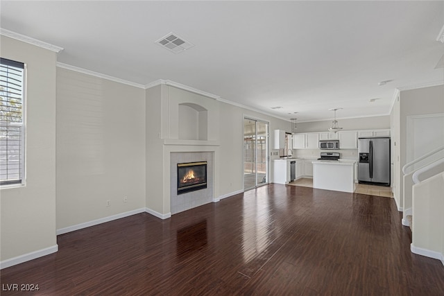 unfurnished living room with ornamental molding, sink, wood-type flooring, and a tile fireplace