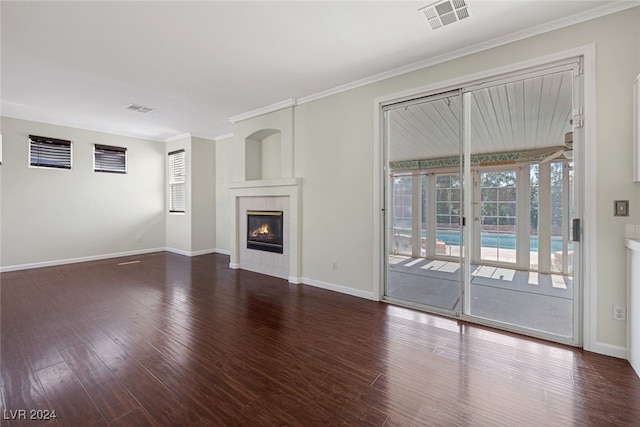 unfurnished living room featuring ornamental molding, dark wood-type flooring, and a tile fireplace