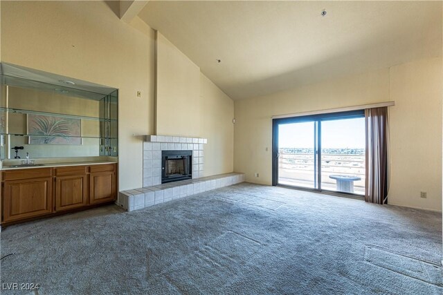 unfurnished living room featuring a tiled fireplace, light carpet, high vaulted ceiling, and sink