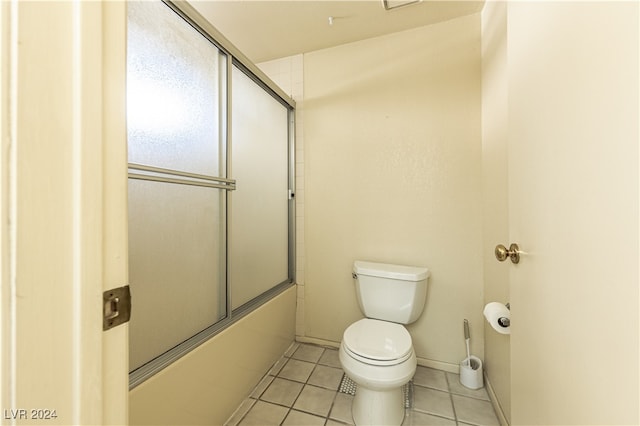 bathroom featuring shower / bath combination with glass door, toilet, and tile patterned floors