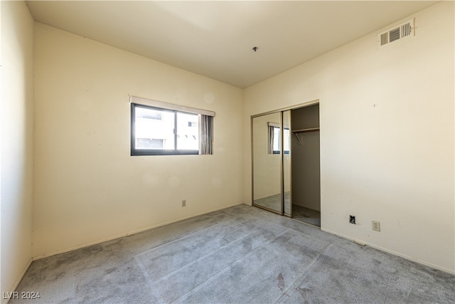 unfurnished bedroom featuring light carpet and a closet