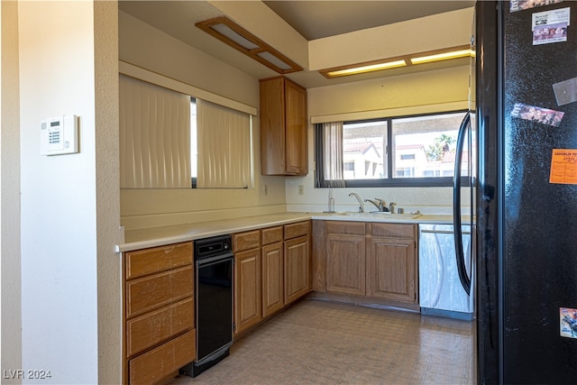 kitchen with black refrigerator, sink, and stainless steel dishwasher