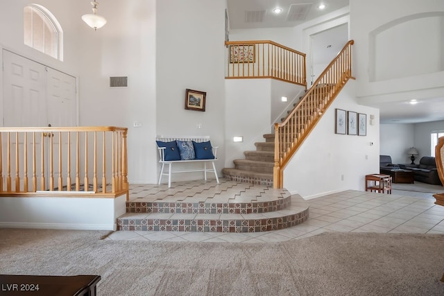 staircase featuring a towering ceiling and carpet floors