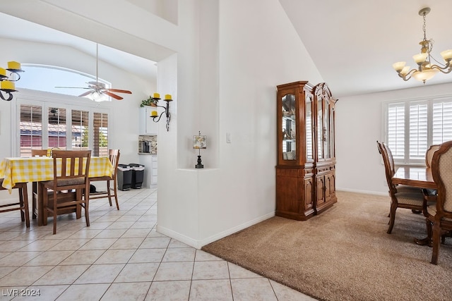 interior space featuring ceiling fan with notable chandelier, lofted ceiling, a wealth of natural light, and light tile patterned floors