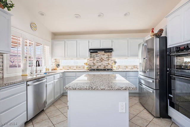 kitchen featuring backsplash, a center island, appliances with stainless steel finishes, lofted ceiling, and white cabinets