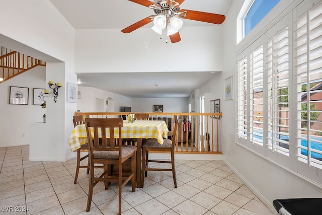 tiled dining space featuring ceiling fan and a high ceiling