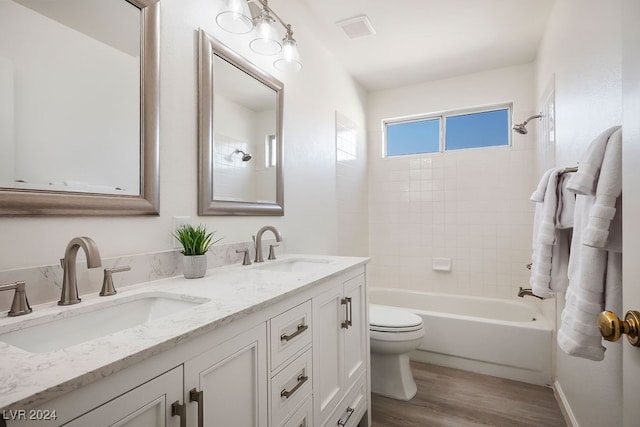 full bathroom with tiled shower / bath combo, vanity, toilet, and wood-type flooring