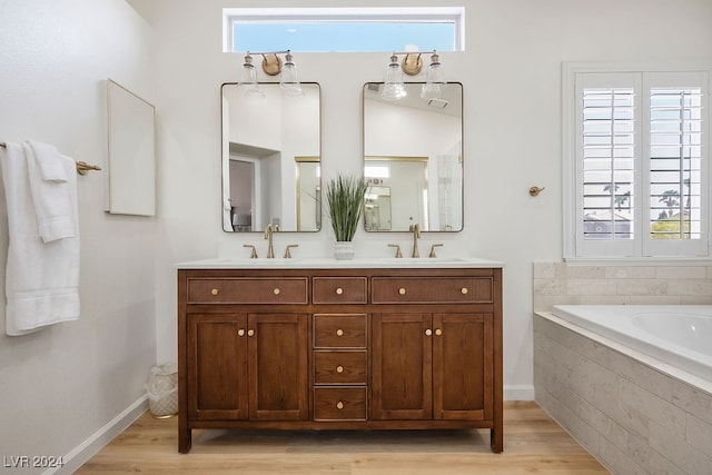 bathroom with tiled tub, vanity, and hardwood / wood-style flooring