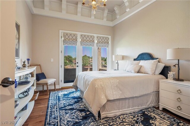 bedroom with a towering ceiling, access to outside, an inviting chandelier, and dark wood-type flooring