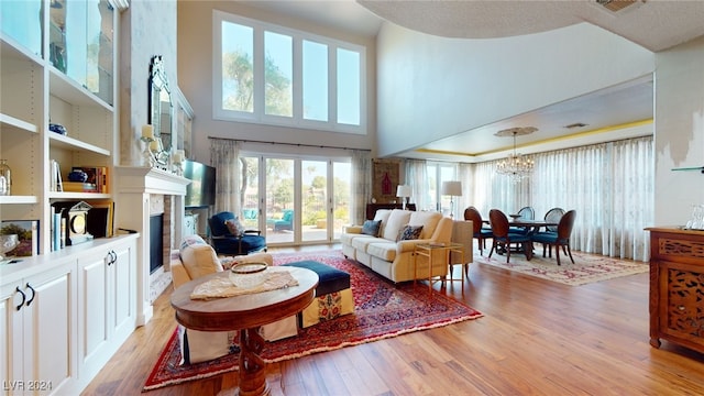 living room with light hardwood / wood-style floors, a high ceiling, and an inviting chandelier