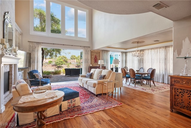 living room featuring light hardwood / wood-style flooring, a chandelier, and a high ceiling