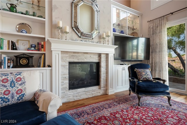 sitting room with a fireplace, wood-type flooring, and built in features