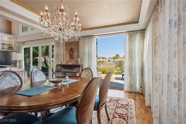 dining space featuring a textured ceiling, light hardwood / wood-style flooring, a notable chandelier, and crown molding