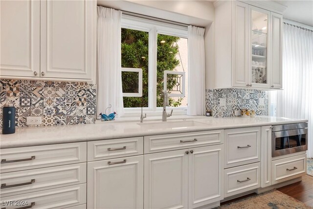 kitchen featuring white cabinets, backsplash, dark wood-type flooring, and sink