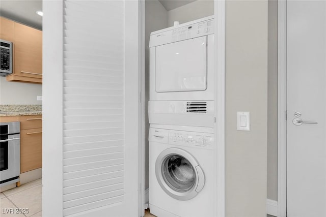 washroom with stacked washer / drying machine and light tile patterned floors