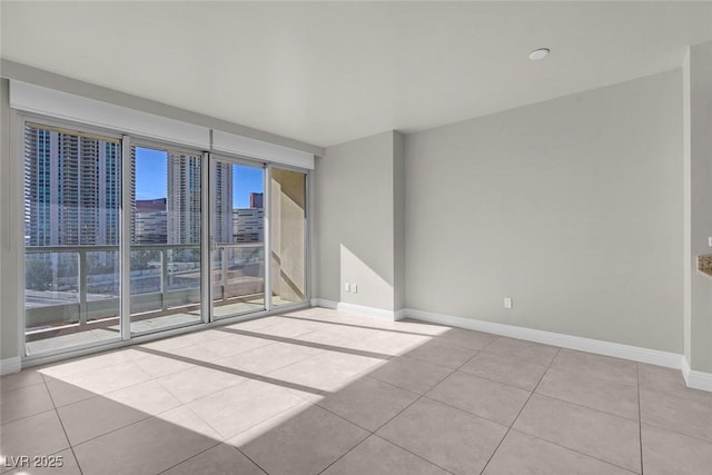 tiled empty room featuring a healthy amount of sunlight and a wall of windows