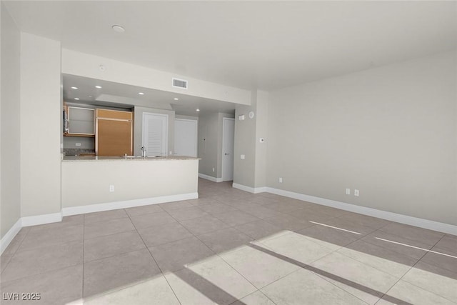 unfurnished living room featuring light tile patterned floors and sink