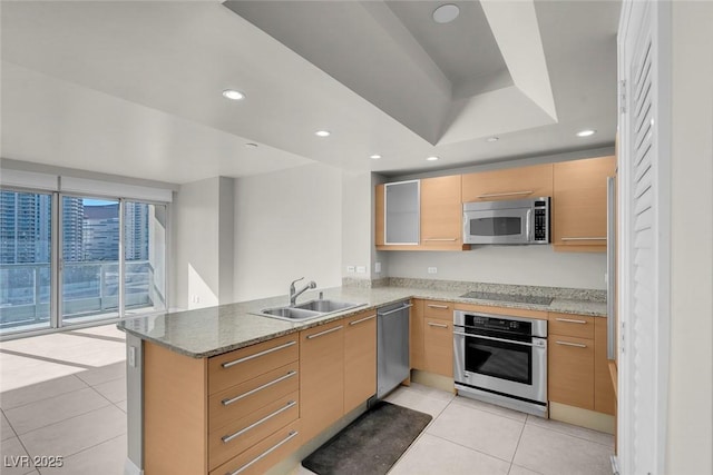 kitchen featuring sink, light stone countertops, appliances with stainless steel finishes, light tile patterned flooring, and kitchen peninsula