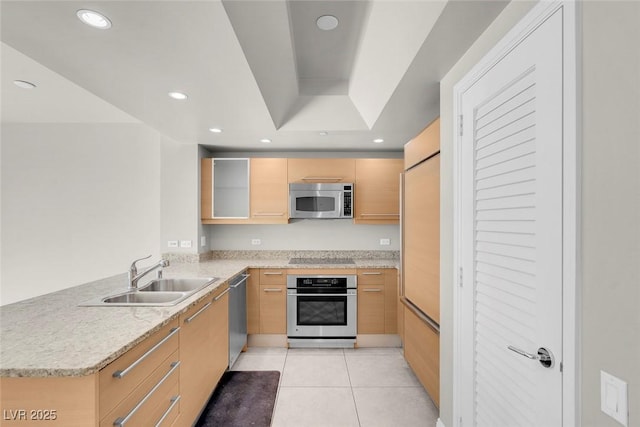 kitchen featuring light brown cabinets, sink, light tile patterned floors, appliances with stainless steel finishes, and kitchen peninsula