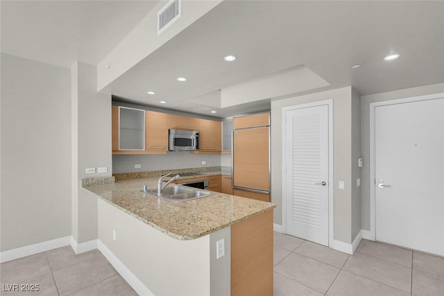 kitchen featuring light stone counters, kitchen peninsula, sink, and light tile patterned floors