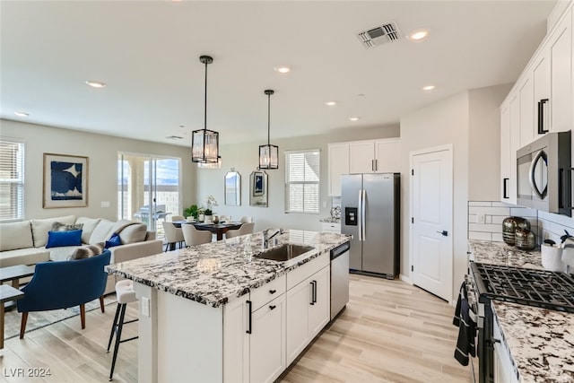 kitchen featuring a kitchen island with sink, light hardwood / wood-style flooring, sink, appliances with stainless steel finishes, and white cabinets