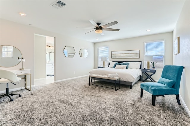 carpeted bedroom with ceiling fan, ensuite bath, and multiple windows