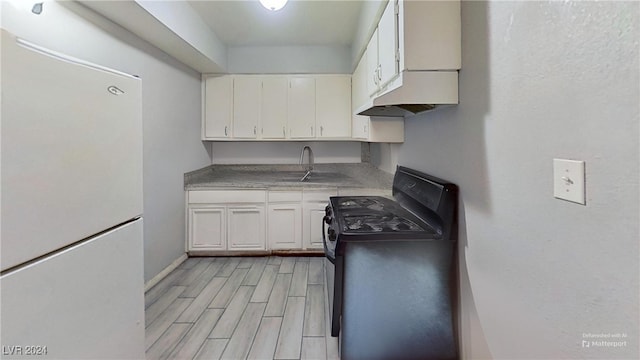 kitchen with white cabinetry, sink, white fridge, black range, and light wood-type flooring