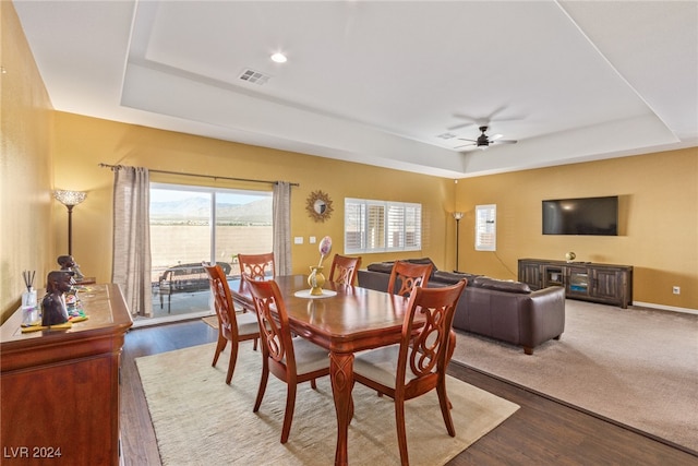 dining room with ceiling fan, wood-type flooring, and a tray ceiling