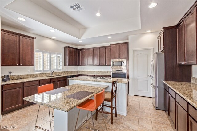 kitchen with light stone counters, appliances with stainless steel finishes, a breakfast bar area, and a kitchen island