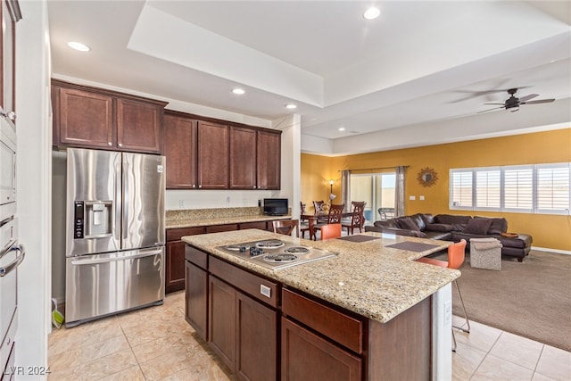 kitchen with light carpet, ceiling fan, stainless steel appliances, dark brown cabinetry, and a center island