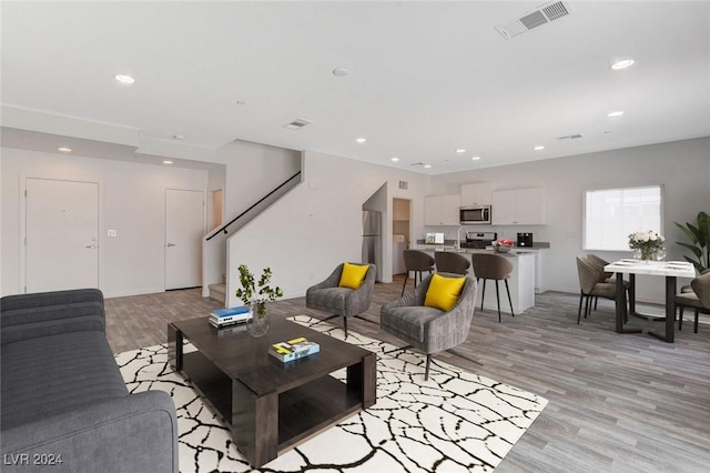 living room with light hardwood / wood-style floors and sink