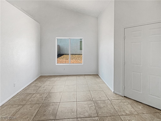 spare room featuring lofted ceiling and light tile patterned floors