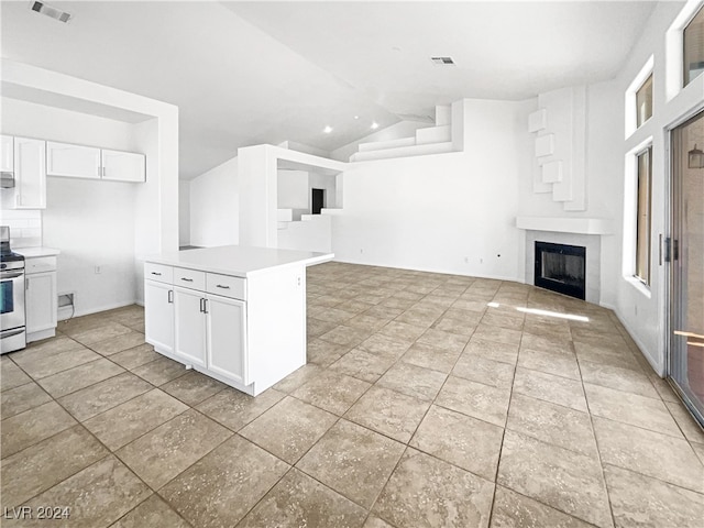 kitchen with lofted ceiling, stainless steel range, and white cabinetry