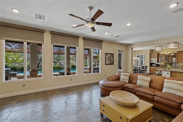 living room featuring sink and ceiling fan with notable chandelier