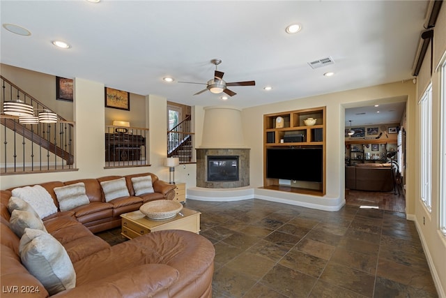 living room featuring built in shelves, ceiling fan, and a fireplace