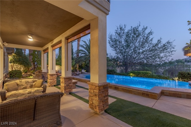 pool at dusk with an outdoor hangout area and a patio area