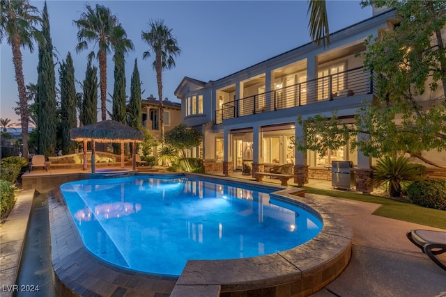 pool at dusk with a patio and a gazebo