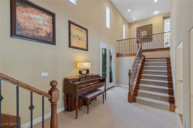 miscellaneous room featuring french doors, a towering ceiling, and light carpet