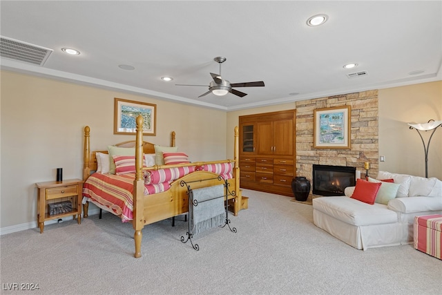 bedroom featuring a fireplace, light carpet, ceiling fan, and crown molding