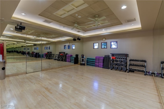 interior space with light wood-type flooring, ceiling fan, and a tray ceiling