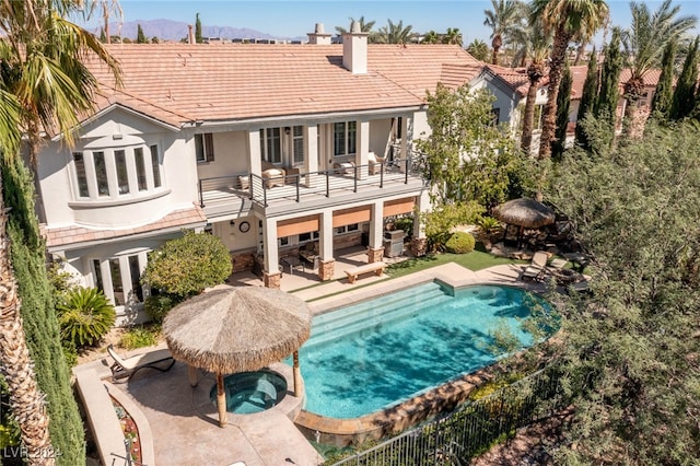 rear view of house with a pool with hot tub, a patio area, cooling unit, and a balcony