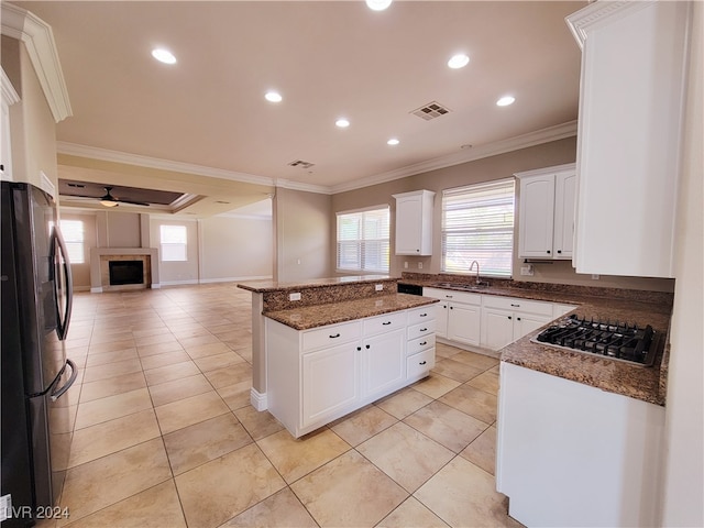 kitchen featuring white cabinets, stainless steel fridge, black gas stovetop, and crown molding