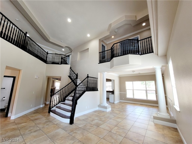 entryway featuring ornate columns, light tile patterned floors, and a high ceiling