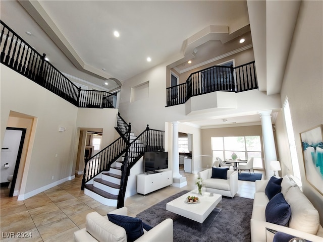 living room with crown molding, light tile patterned floors, ornate columns, and a towering ceiling